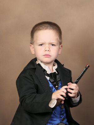 Owen dressed as a cowboy, with a surly look on his face and holding a pistol.